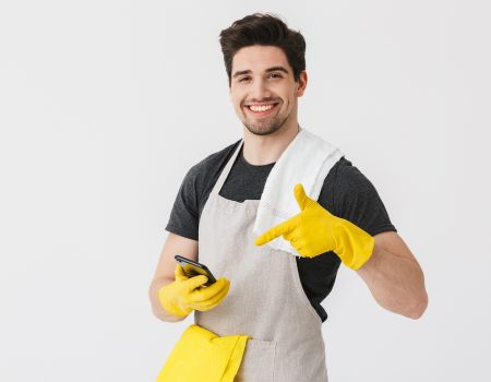 Handsome brunette houseman wearing apron Handsome brunette houseman wearing apron standing isolated over white background, showing mobile phone